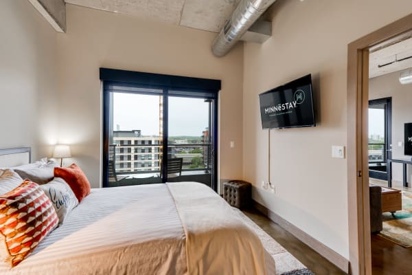 Beautiful bedroom featuring a king-size bed, decorative pillows, a lamp, and a balcony view of the cityscape.