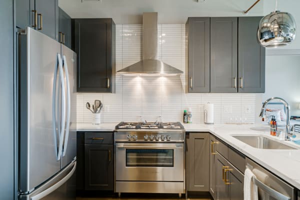 Modern kitchen with gray cabinets and stainless steel appliances.