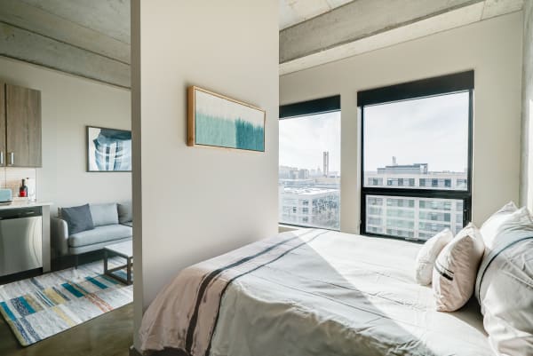 Modern bedroom with large windows offering city views and contemporary decor.
