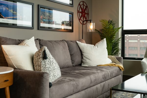 A living room with a grey sofa, decorative pillows, and cityscape artwork.