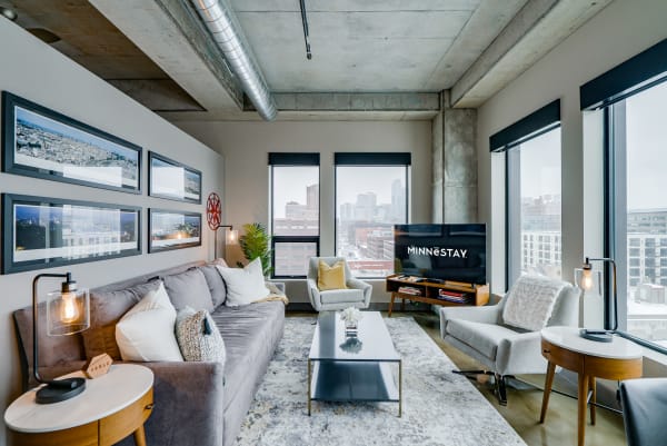Stylish living room with gray sofa, city skyline view, and modern decor.