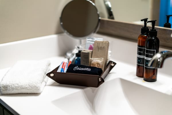 An organized bathroom sink featuring a towel, toiletries in a brown tray, and lotion and soap bottles.