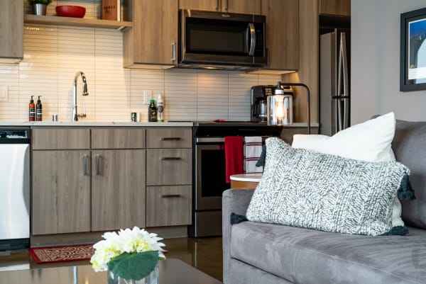 Modern kitchen with wooden cabinets and gray couch in the living room