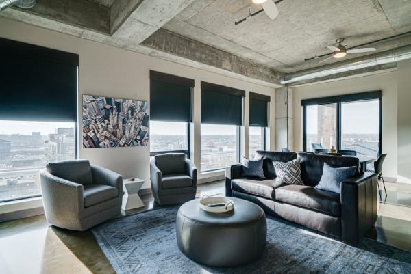 Modern living room with a large window, stylish furniture, and cityscape artwork.