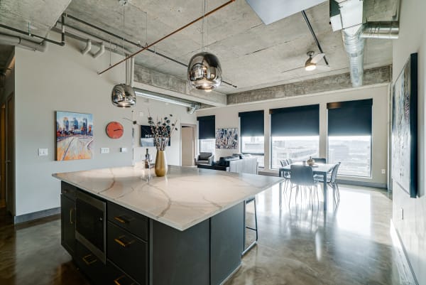 Interior view of a modern apartment kitchen with marble island and city skyline.