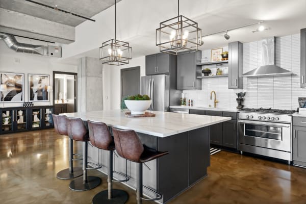 Modern kitchen featuring a marble countertop island, dark cabinetry, and stylish lighting.