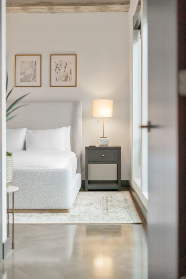 Modern bedroom with a white bed, nightstand, and framed art on the wall.