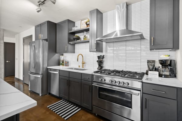 Modern kitchen with dark cabinets, golden fixtures, and stainless steel appliances.