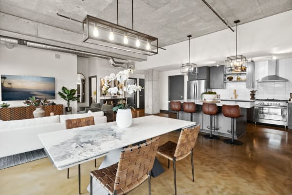Modern apartment interior featuring a dining area, living room, and kitchen with sleek furniture and lighting.