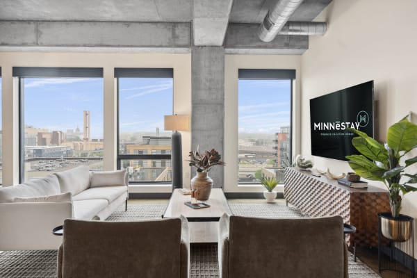 A stylish living room featuring large windows, modern furniture, and city views.