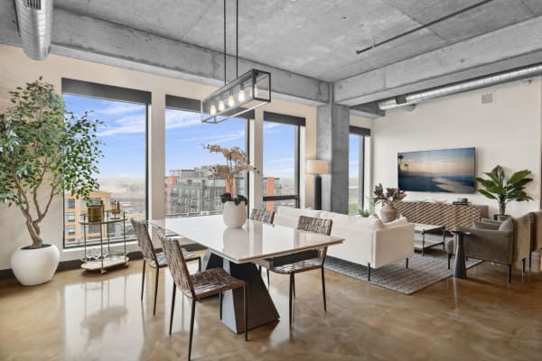 A modern dining and living area with large windows, a marble table, and plush seating.