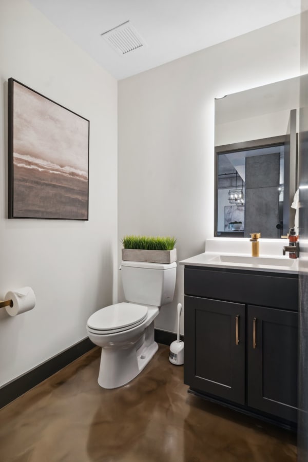 Modern bathroom with abstract art, a black vanity, and polished concrete floor.