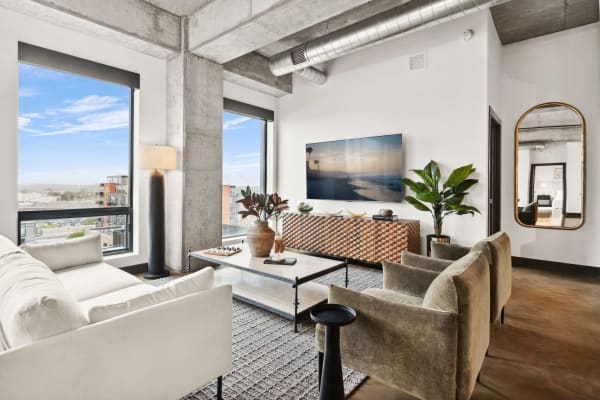 Stylish living room featuring concrete walls, large windows, and a cozy sofa.