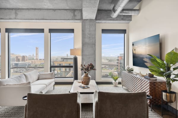 Modern living room with large windows, concrete details, and stylish decor.
