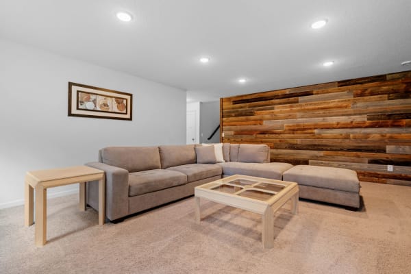 Cozy living room with gray sectional sofa and wooden accent wall.