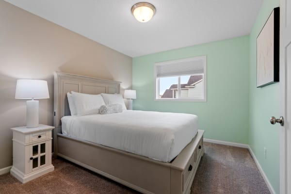 Cozy bedroom with a light wood bed, white bedding, and mint green walls.