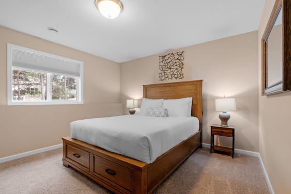 A serene bedroom with a wooden bed, soft white bedding, and natural light from the window.