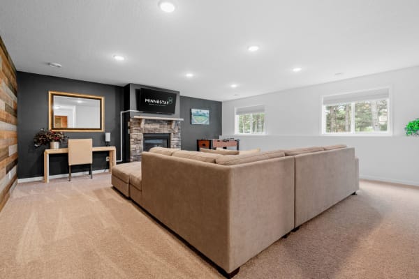 Cozy living room featuring a beige sectional sofa, stone fireplace, and modern decor.