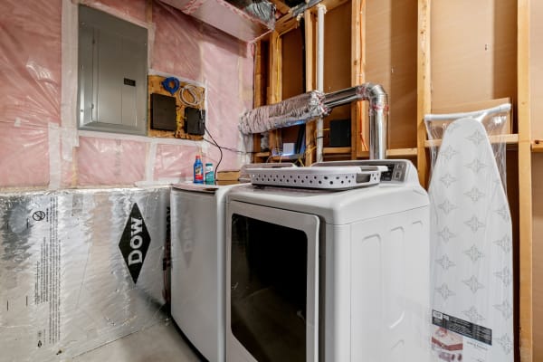 Laundry area with washing machine, dryer, and ironing board in a basement.