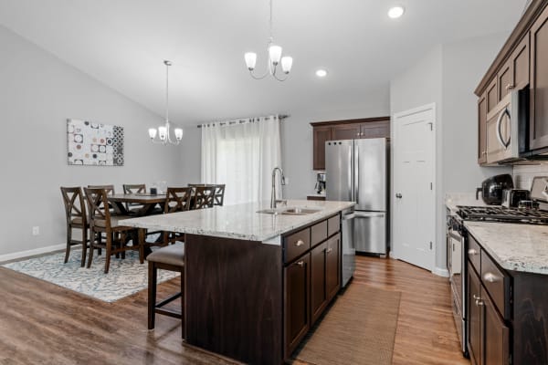 Contemporary kitchen with a dining area, dark cabinets, granite countertop, and natural light.