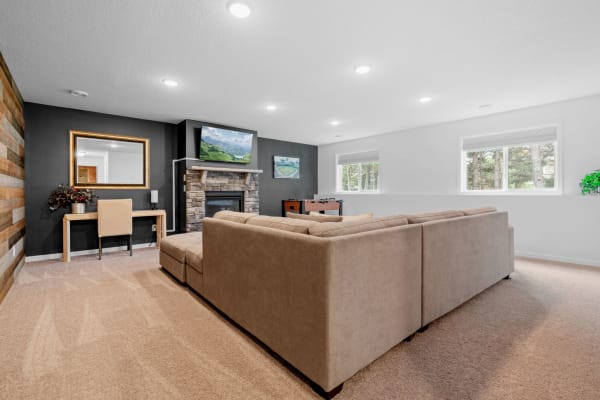 Modern living room with a beige sectional couch, fireplace, and large windows.