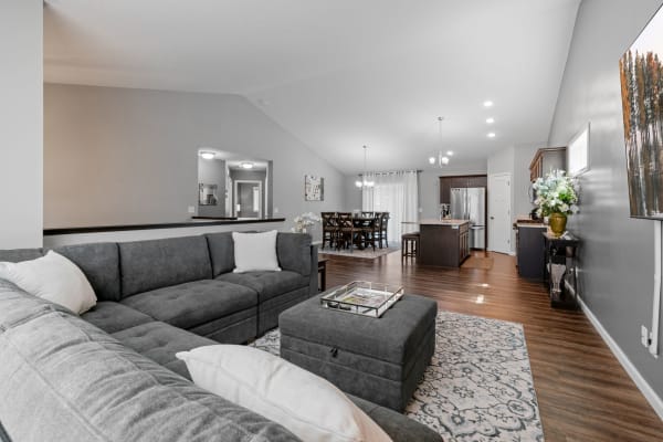 Open-concept living room with a sectional sofa and dining area in the background.