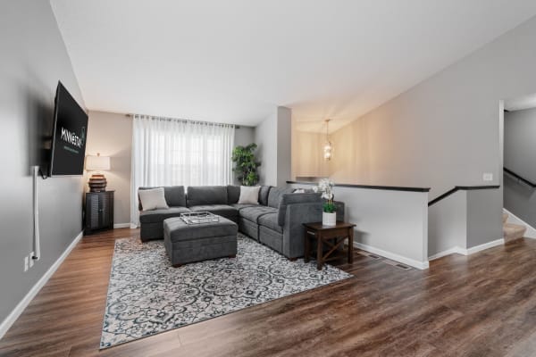 A modern living room featuring a grey sectional sofa, an area rug, and natural light from a large window.