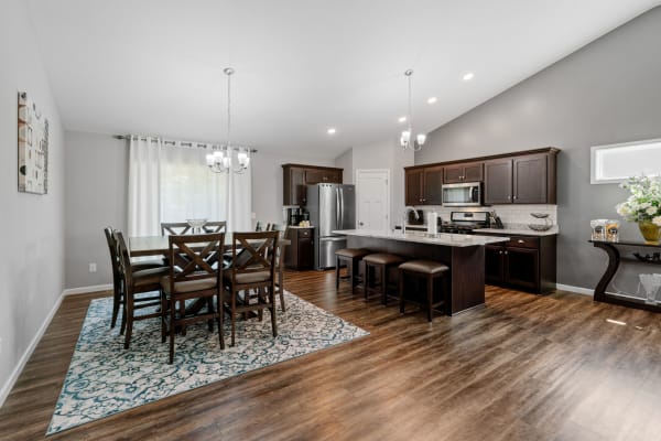 Modern kitchen and dining area with dark wooden furniture, stainless steel appliances, and a decorative rug.