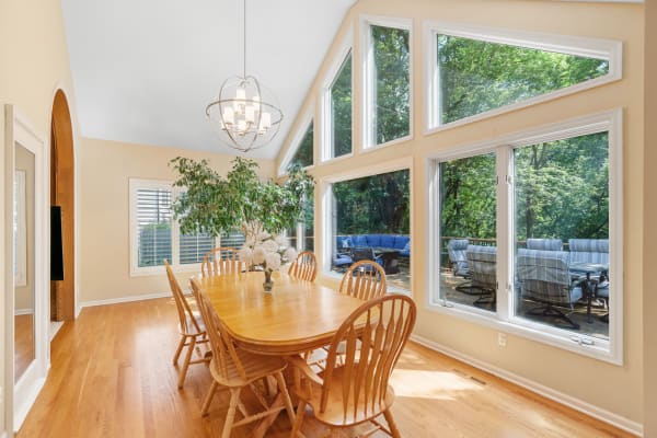 Spacious dining room with wooden table, large windows, and indoor plant.