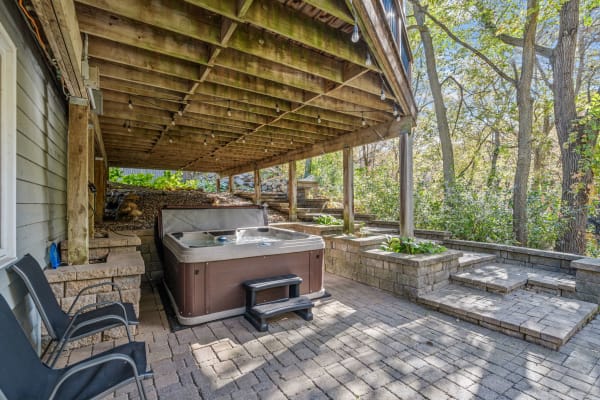 A hot tub under a wooden deck in a landscaped outdoor space.