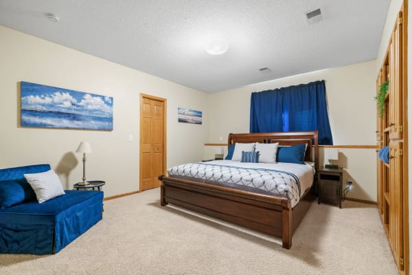 An inviting bedroom with a wooden bed, blue decor, and soft carpet.