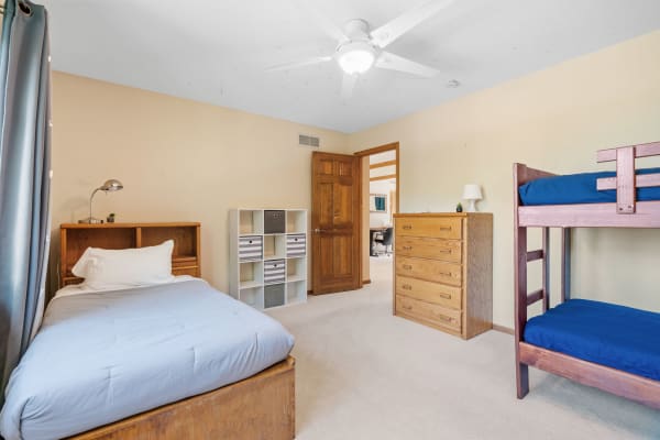 Cozy bedroom featuring a single bed, bunk bed, dresser, and bookshelf.