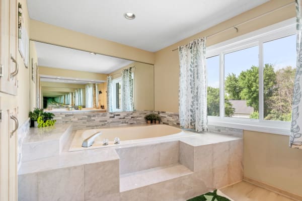 Spacious bathroom with a bathtub, large window, and elegant decor.