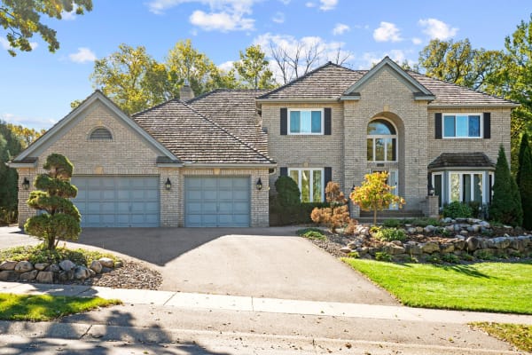 Front view of a two-story house with brick exterior and landscaped yard.