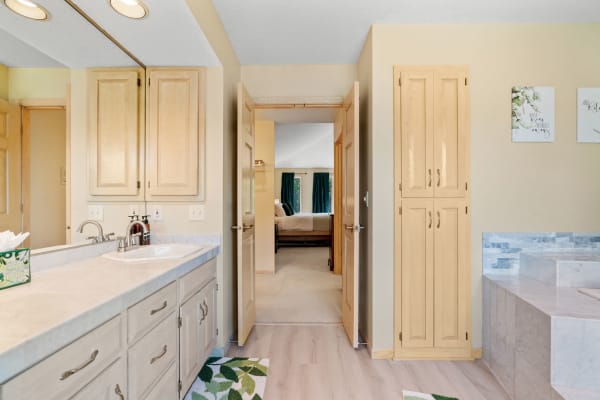 Bright bathroom with marble counters and light wood cabinetry.
