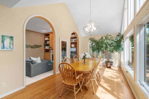 A spacious dining area featuring a wooden table, chairs, and a view of a cozy living room.