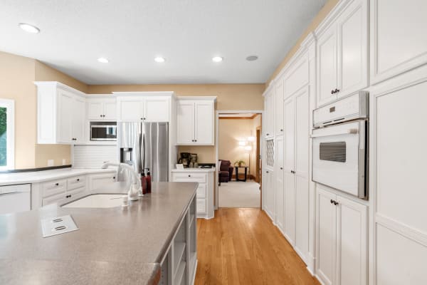 A spacious kitchen with white cabinets, a central island, and stainless steel appliances.