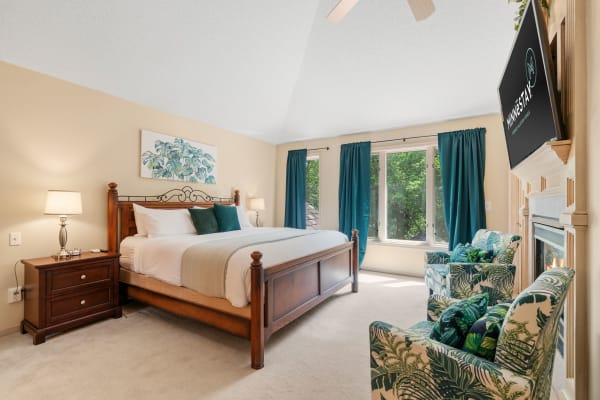 Elegant bedroom with a wooden bed, teal curtains, and botanical decor.