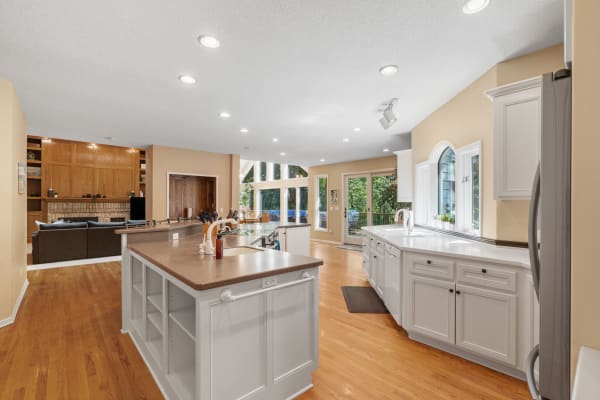 A spacious kitchen with white cabinets, a central island, and large windows allowing natural light.