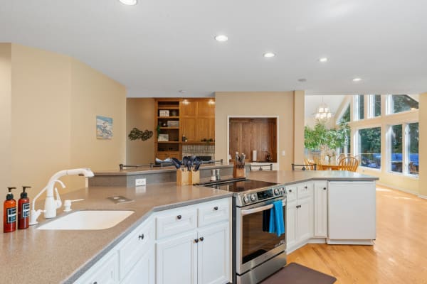 Modern kitchen with white cabinets and a spacious layout, featuring stainless steel appliances and a dining area.