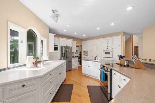 A pristine kitchen featuring white cabinets, stainless steel appliances, and wood flooring.