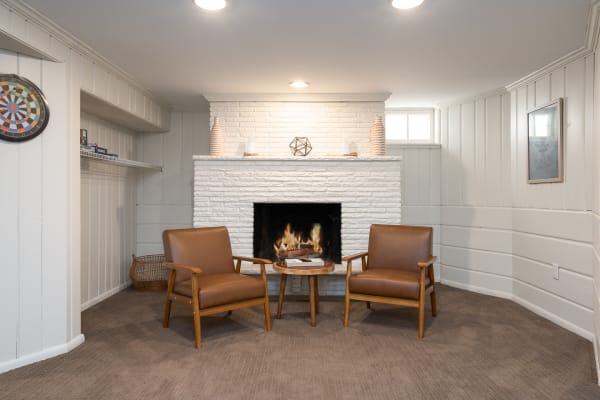 Cozy living room with brown leather armchairs and a white brick fireplace.