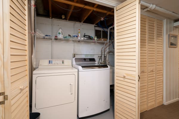 Laundry room with washing machine, dryer, and shelf of cleaning products.