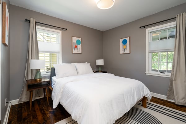 Cozy modern bedroom with white bedding and geometric art.