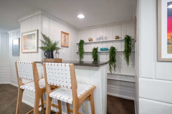 A contemporary kitchen nook featuring bar stools, a granite countertop, and decorative elements on the walls.