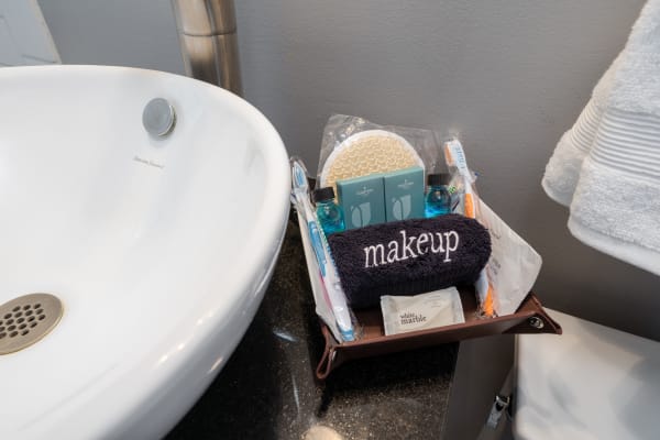 Bathroom countertop with a white sink and a wooden tray containing toiletries and a blue towel labeled 'makeup.'