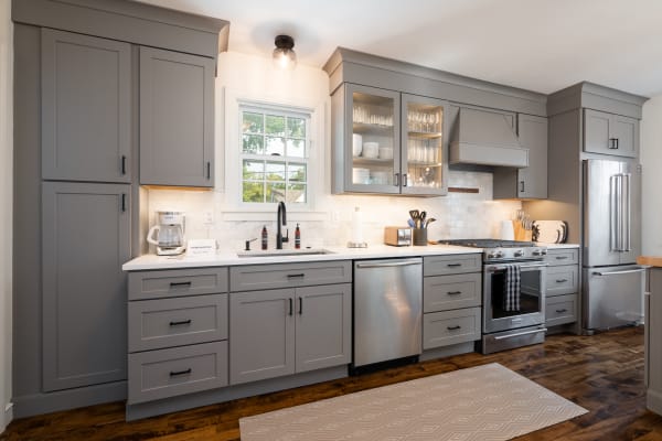 A contemporary kitchen with gray cabinets, white countertops, and stainless steel appliances.
