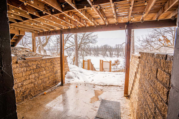 An outdoor patio with string lights and a view of snow-covered ground and trees.