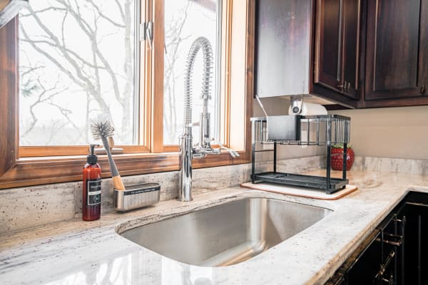 Modern kitchen sink with stainless steel basin, stylish faucet, and dish drying rack.