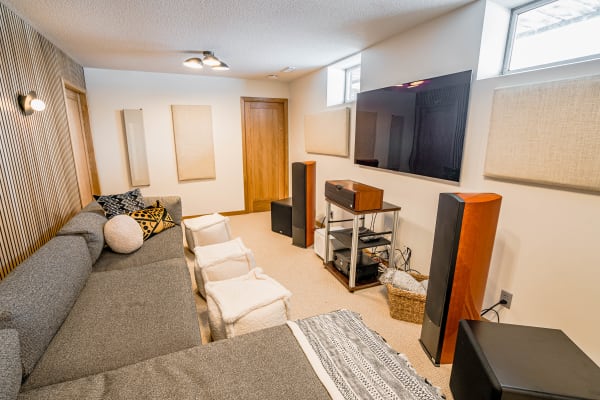 A cozy entertainment room with a grey couch, decorative pillows, and audio equipment.